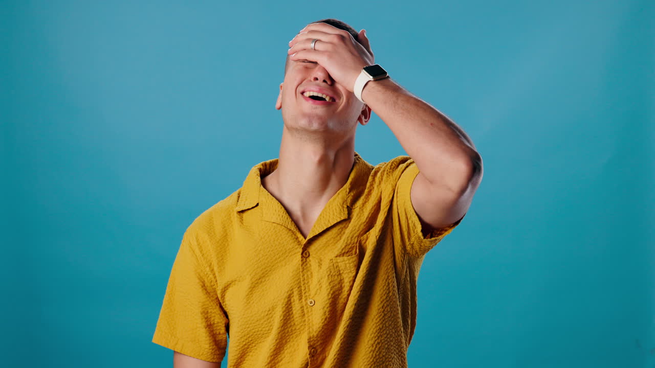 Man in yellow shirt with facepalm gesture