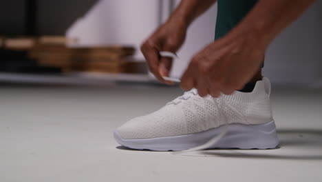 close up of female athlete in gym or changing room tying laces of training shoe before exercising 1