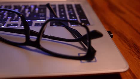 slider shot panning right to left of glasses resting on top of a laptop computer with a coffee mug in the foreground