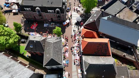 aerial top down of crowded city streets of dutch town. sunny day in spring. kings day in netherlands. flyover shot. small historic buildings and walking people.
