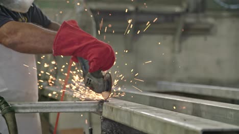 slow motion of a worker using metal grinder with sparks flying at a metal shop