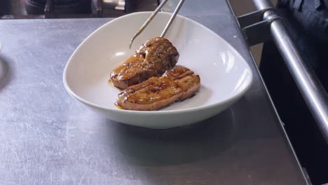detalle del plato de las manos del hombre emplatando porciones de foie gras en el plato antes de servirlo a los clientes