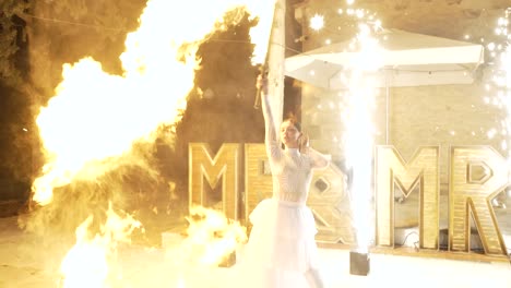 fire performer in white dress at night wedding show with sparks and flames