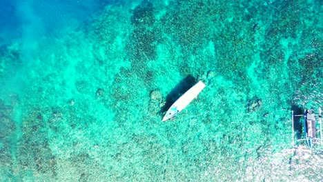 Touring-boats-floating-over-crystal-emerald-water-of-turquoise-lagoon-full-of-coral-reefs-and-pebbles-on-sea-bottom-in-Malaysia