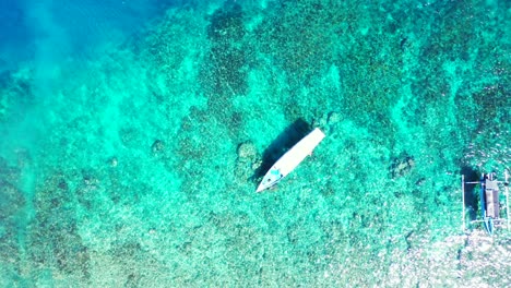 barcos de turismo flotando sobre el agua esmeralda cristalina de la laguna turquesa llena de arrecifes de coral y guijarros en el fondo del mar en malasia