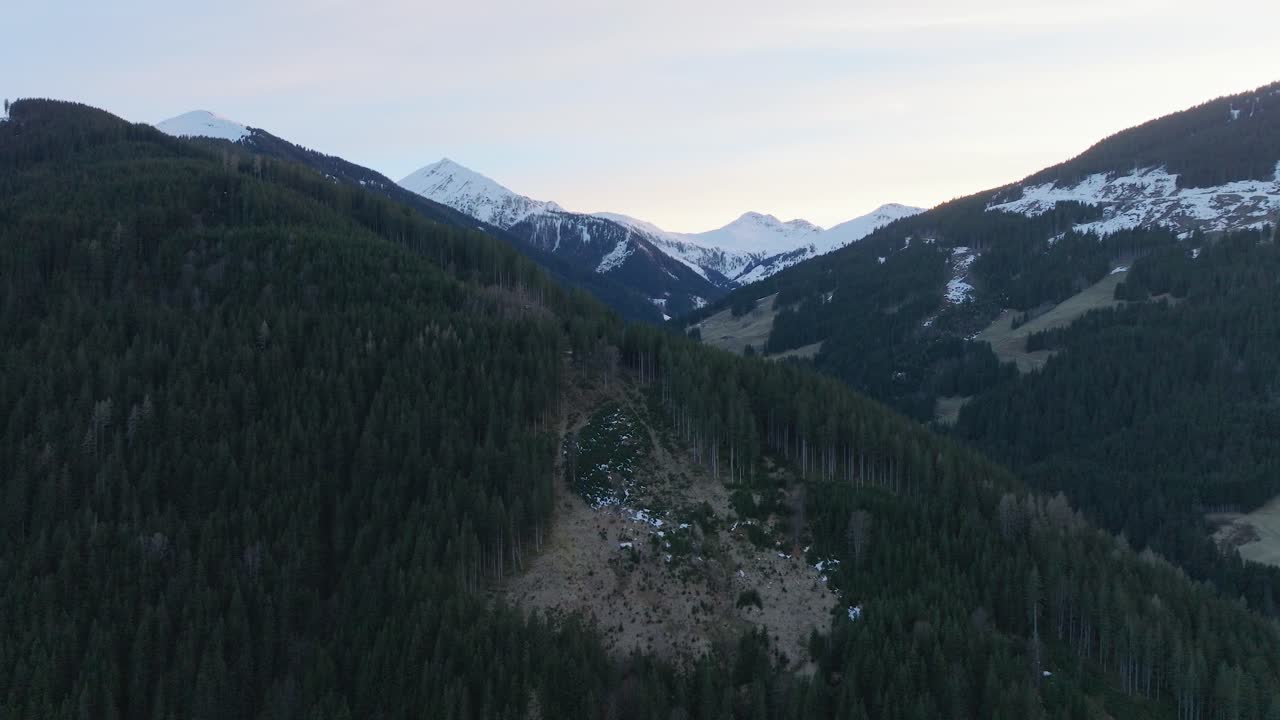 la estación de esquí de saalbach-hinterglemm en austria con montañas cubiertas de nieve durante el anochecer, vista aérea