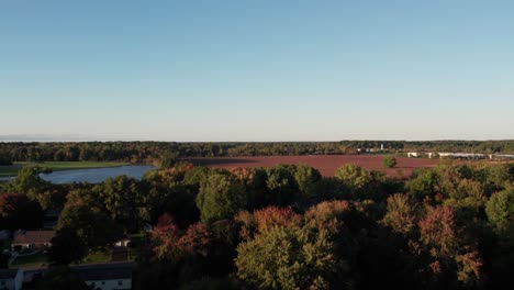 an aerial shot of small town with colorful fields and trees in autumn in the day time