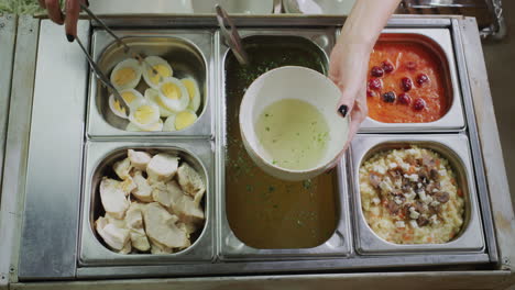 a woman puts soup ingredients into a bowl of broth. delicious all inclusive meals