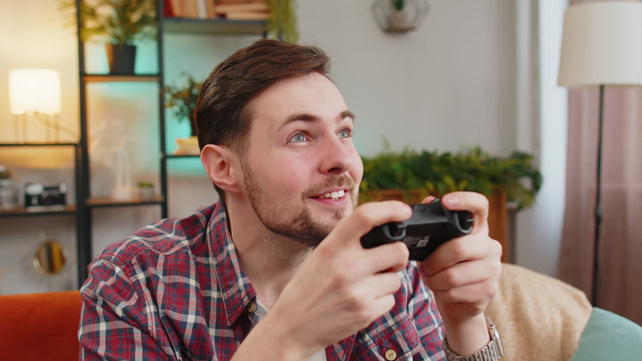 hombre usando un controlador de joystick jugando a juegos de televisión en la consola de video disfrutando en el sofá de la habitación de casa