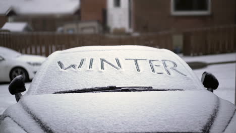 invierno escrito en el parabrisas del coche cubierto de nieve