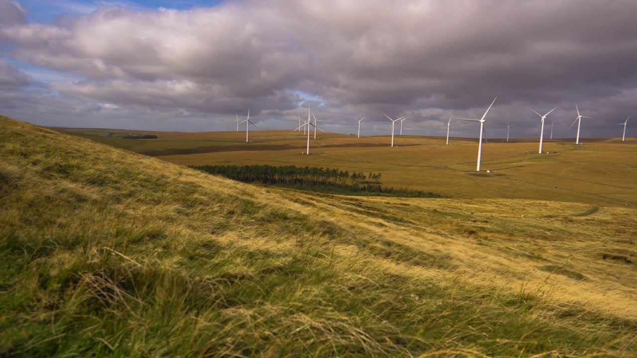 Fast Spinning Wind Turbines Timelapse in Natural Environment with Dark Clouds Passing Above. Clean Energy Generation in Wales, UK