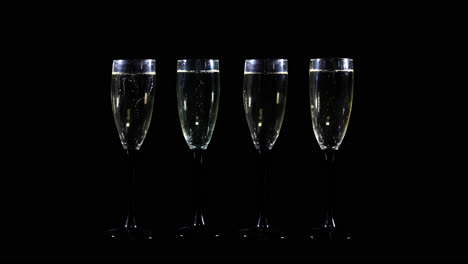 four champagne flutes on black background
