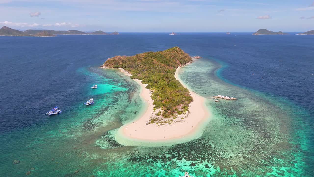 Aerial view of Manlihan Island in Linapacan, Philippines featuring turquoise waters, coral reefs, boats, and lush greenery surrounded by the vast Sulu Sea