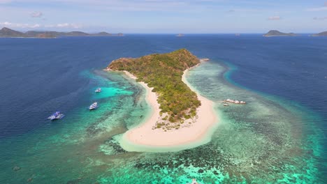 aerial view of manlihan island in linapacan, philippines featuring turquoise waters, coral reefs, boats, and lush greenery surrounded by the vast sulu sea