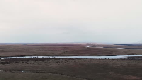 river between wide plains and fields in cloudy weather, iceland