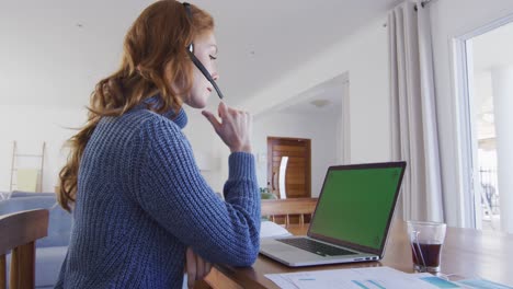 woman wearing headphones using laptop at home