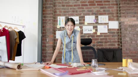 portrait of happy asian female designer at work in fashion design studio in slow motion