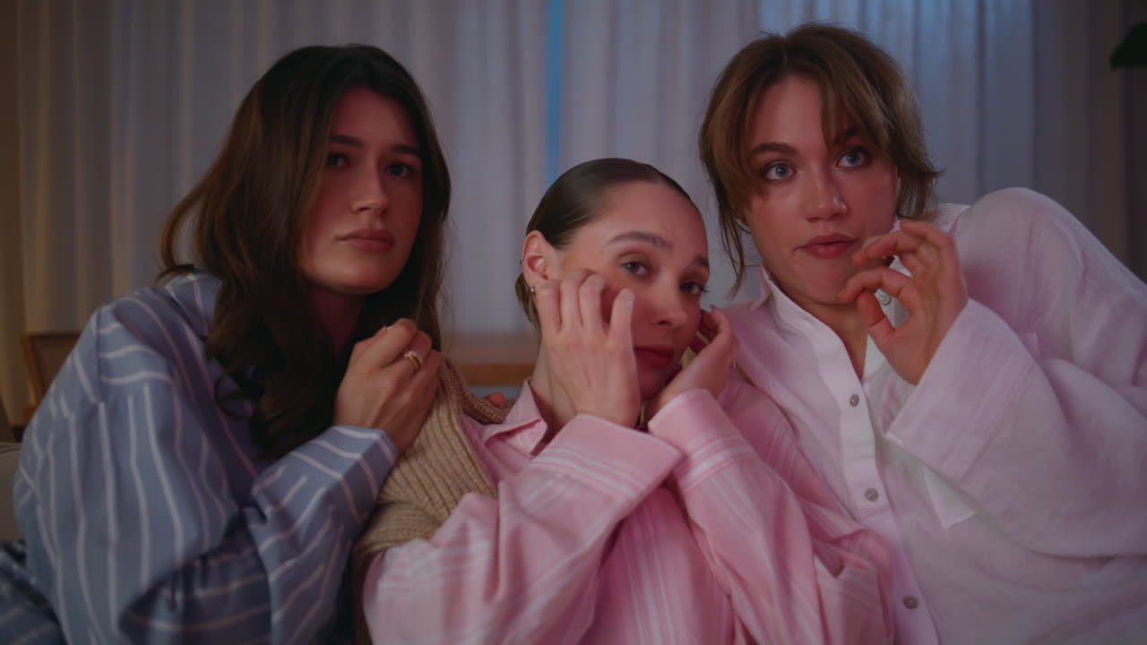Frightened friends watching movie at night home closeup. Tensed women scared