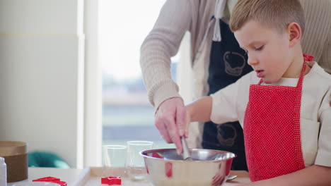 el padre ayuda al niño a golpear huevos en el cuenco mientras cocinan juntos