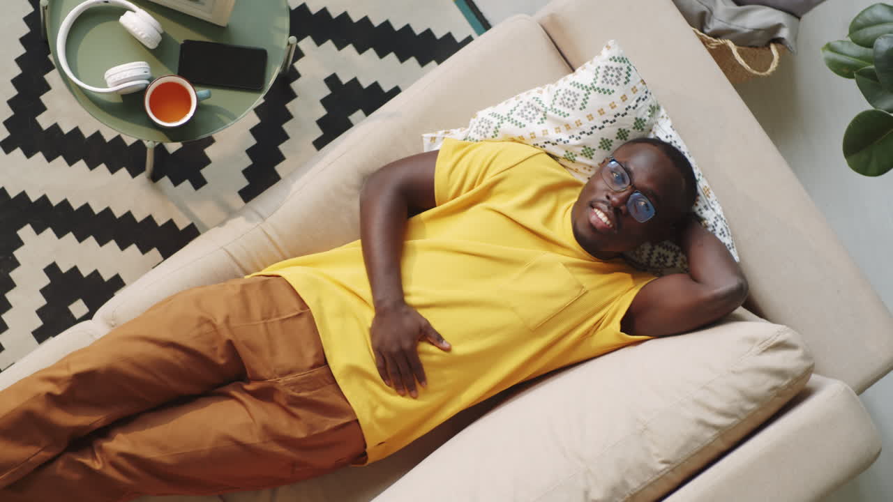 Afro-American Man Lying on Sofa and Posing for Camera