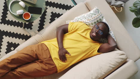 afro-american man lying on sofa and posing for camera