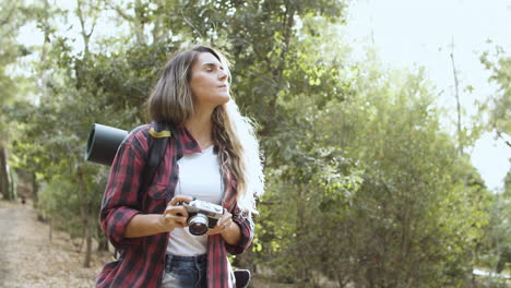 inspired backpacker girl with camera taking pictures of forest