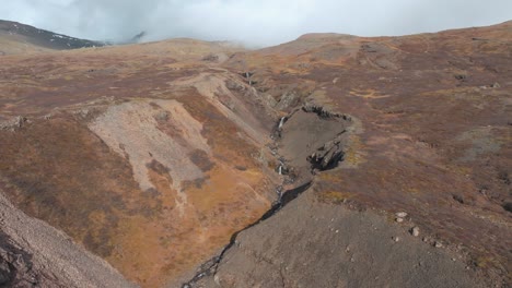 mountain creek cascading down a mountain in iceland in autumn - aerial flyover