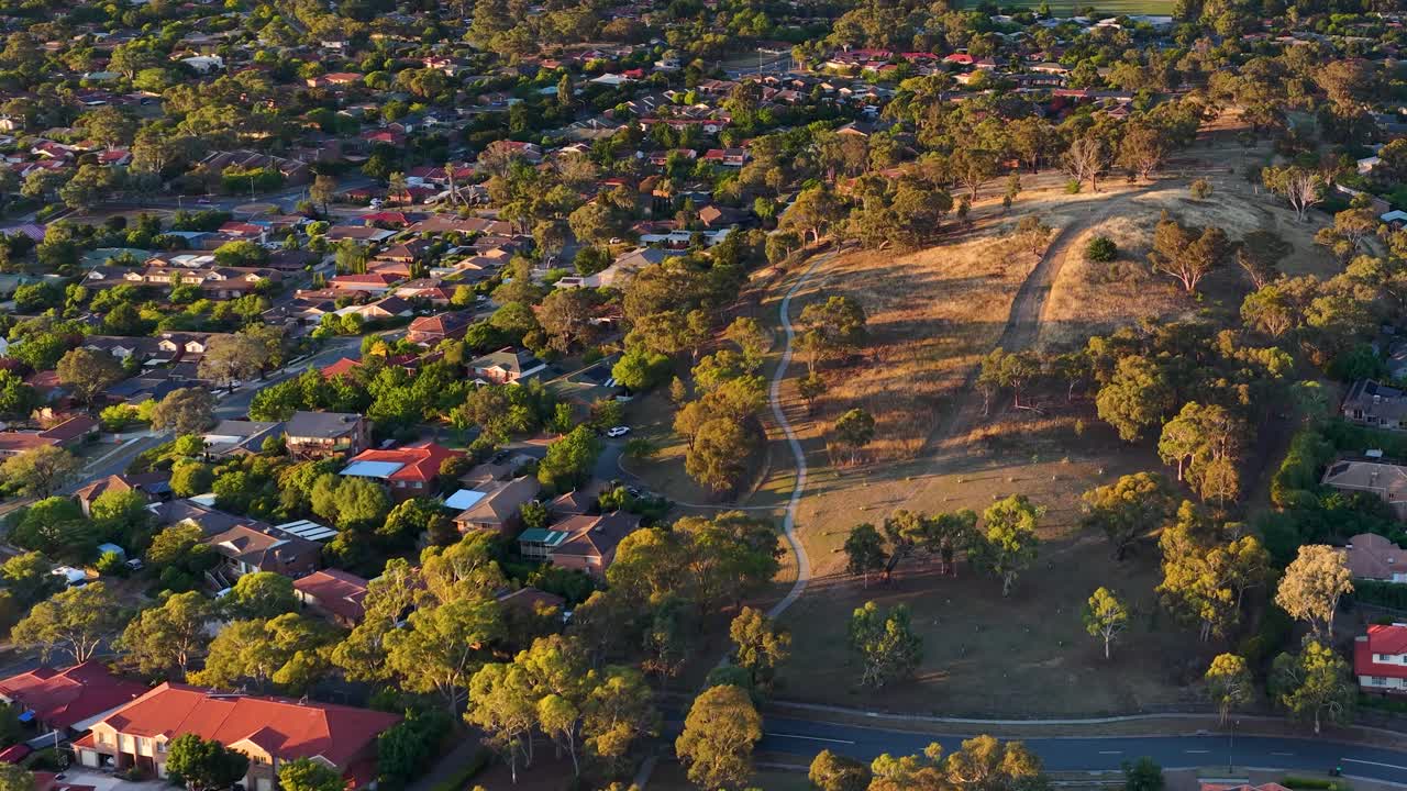 Ripresa aerea di un quartiere periferico e di un parco a Canberra durante la calda luce dell'ora d'oro