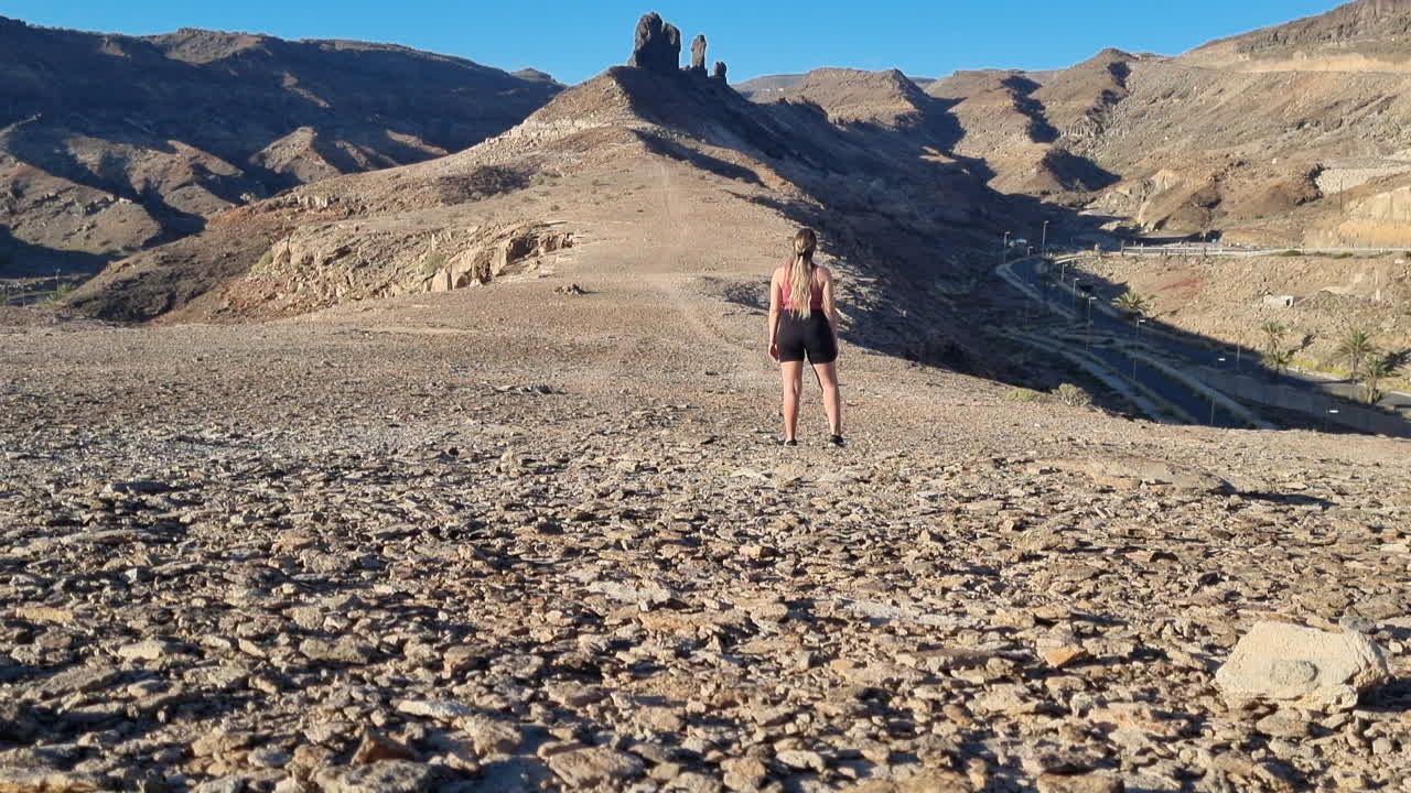 mujer joven observa la formación rocosa llamada el camello, cerca de la playa de medio almud en la isla de gran canaria en un día soleado