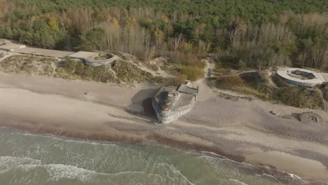 an aerial view of an abandoned ww2 defense bunker with cannon emplacements on the baltic seashore