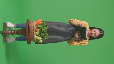 woman in apron using tablet to display fresh vegetables