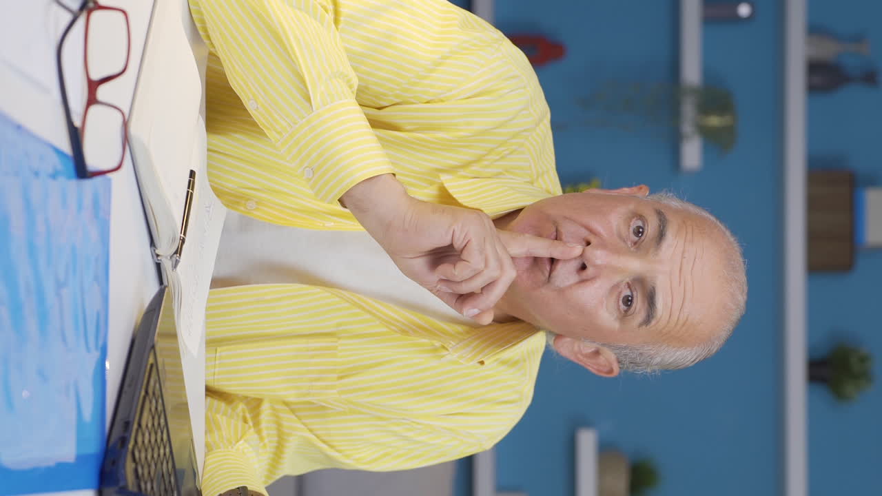 вертикальное видео домашнего офисного работника, старик говорит "шшш" в камеру.