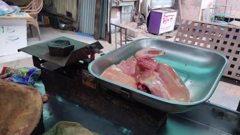 a butcher puts raw chicken breasts on a plate on a weighing scale to prepare delicious food at home