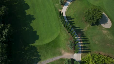 Aerial-Birds-Eye-View-Flying-Overhead-Green-Golf-Course-Fairway-With-Path-Running-In-The-Middle