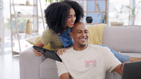 Couple,-tablet-and-laptop-on-sofa-in-home