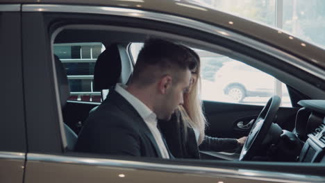 couple test driving a new car in dealership