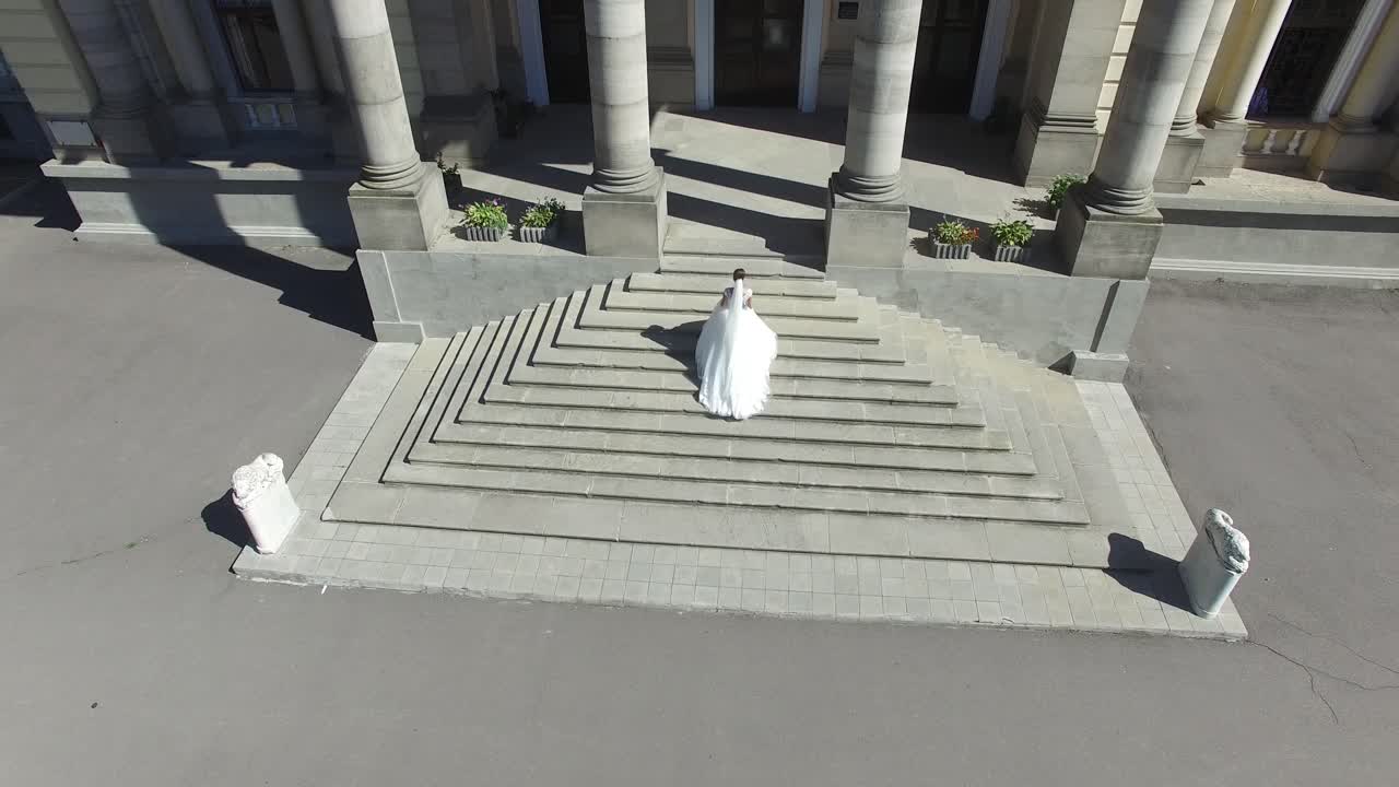 Beautiful Bride Near The House. Aerial shot of a gorgeous young bride walking near old building