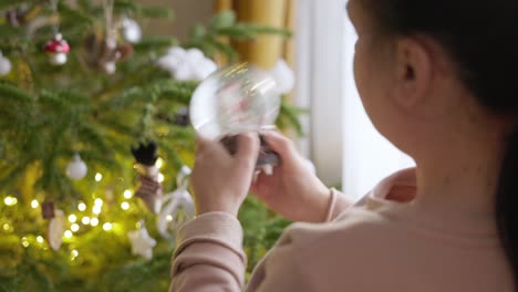 a girl is turning the key of the christmas globe - close up