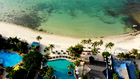 drone tilting upwards showing the buildings of a resort in thongson bay, the fine sandy beachfront, and the crystal clear waters of the gulf of thailand, in koh samui island in surat thani province
