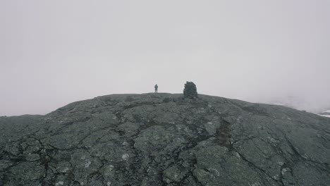 aerial view of hiker standing on store ishaug mountain ledge looking over snow covered landscape