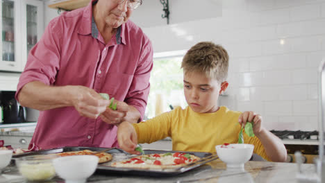 Feliz-Abuelo-Caucásico-Y-Nieto-Haciendo-Pizza-En-La-Cocina,-Cámara-Lenta