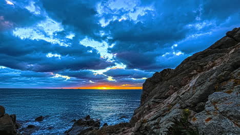 puesta de sol en el horizonte del otro lado del fiordo visto desde la costa rocosa - lapso de tiempo de movimiento deslizante dinámico y paisaje nuboso