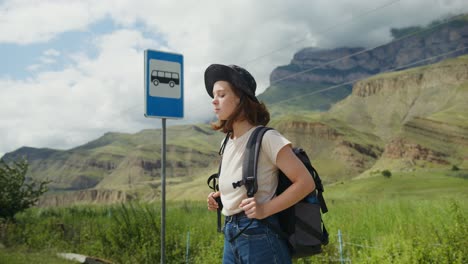 woman with backpack at a bus stop in the mountains