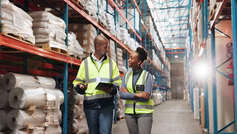 two warehouse workers discuss inventory on a tablet