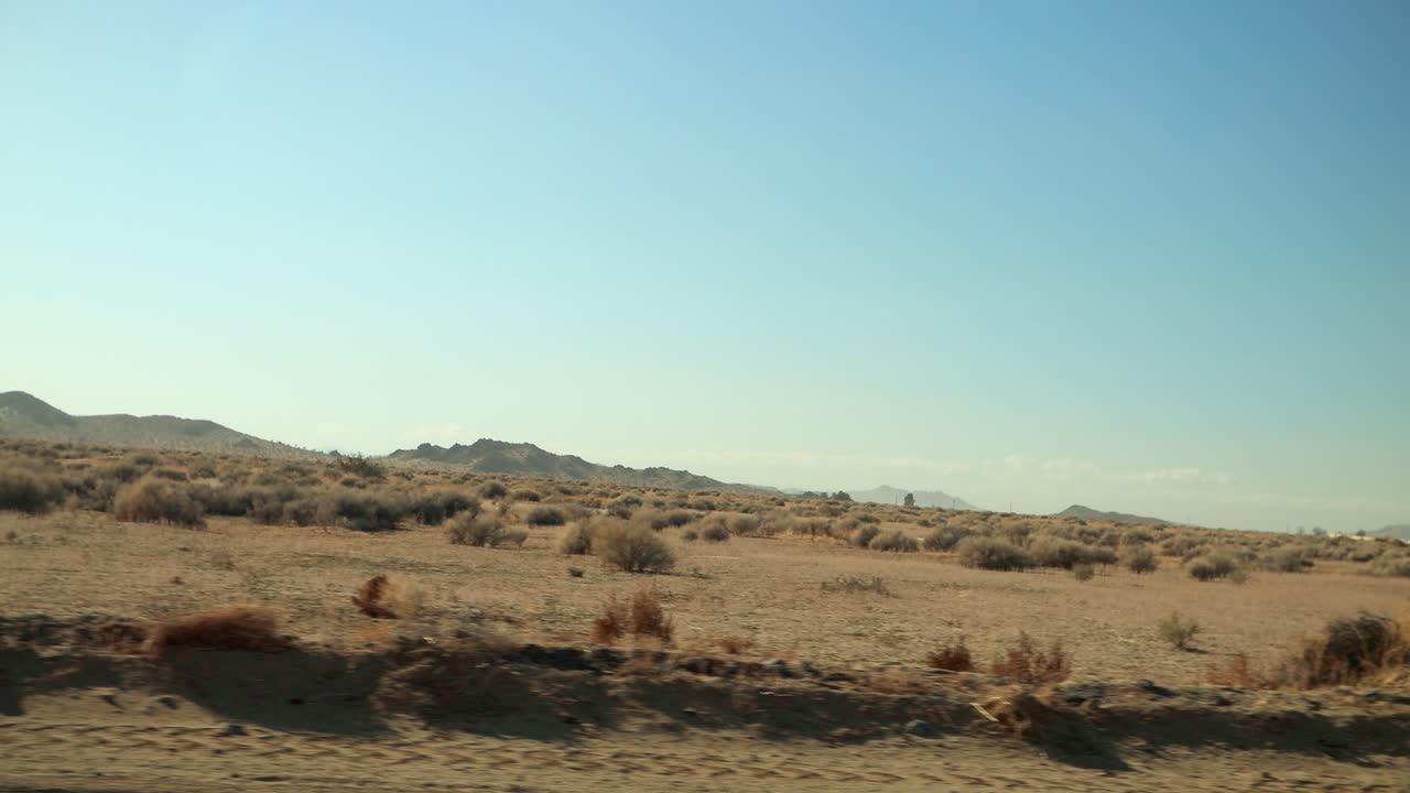 멀리 산이 있고 마른 관목이 지나가는 사막 한가운데 비포장 도로를 빠르게 운전합니다.