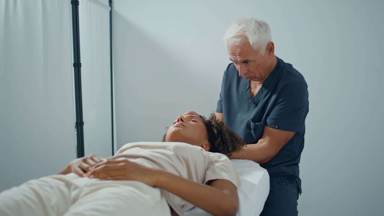 clínica osteópata masajeando mujer presionando la cabeza. hombre enfocado examinar