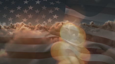 animation of glowing spots and sun shining on sky with clouds over american flag