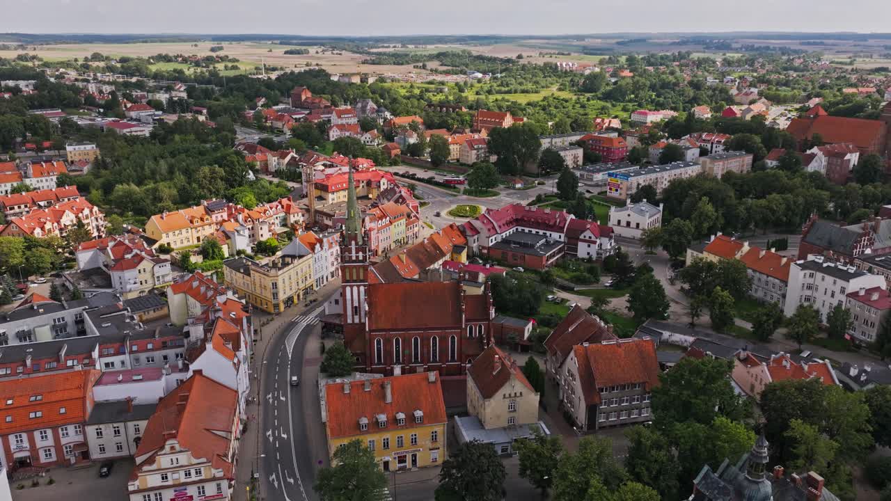 Drone pull back shows Saint Catherine Church blending with Polish countryside