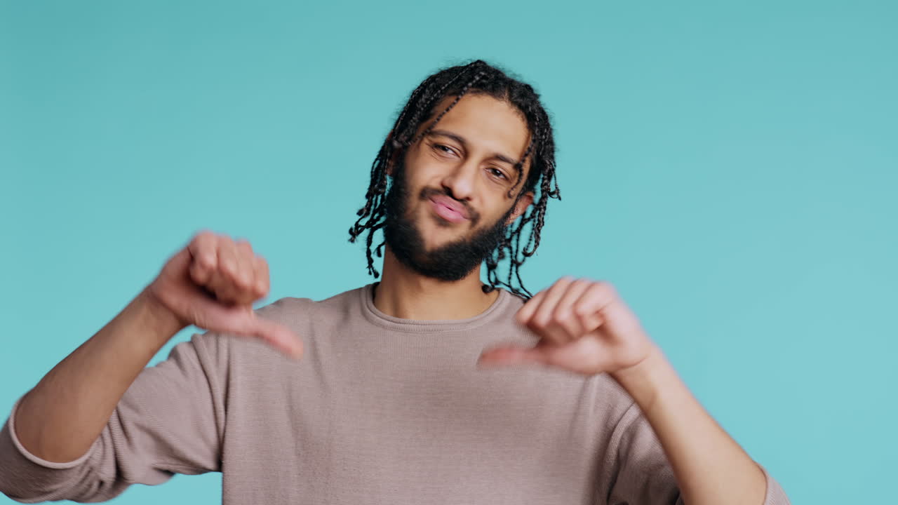 화가 난 남자가 엄지손가락을 내려놓고 몸짓을 하고, 불쾌감을 표하고, 스튜디오 배경