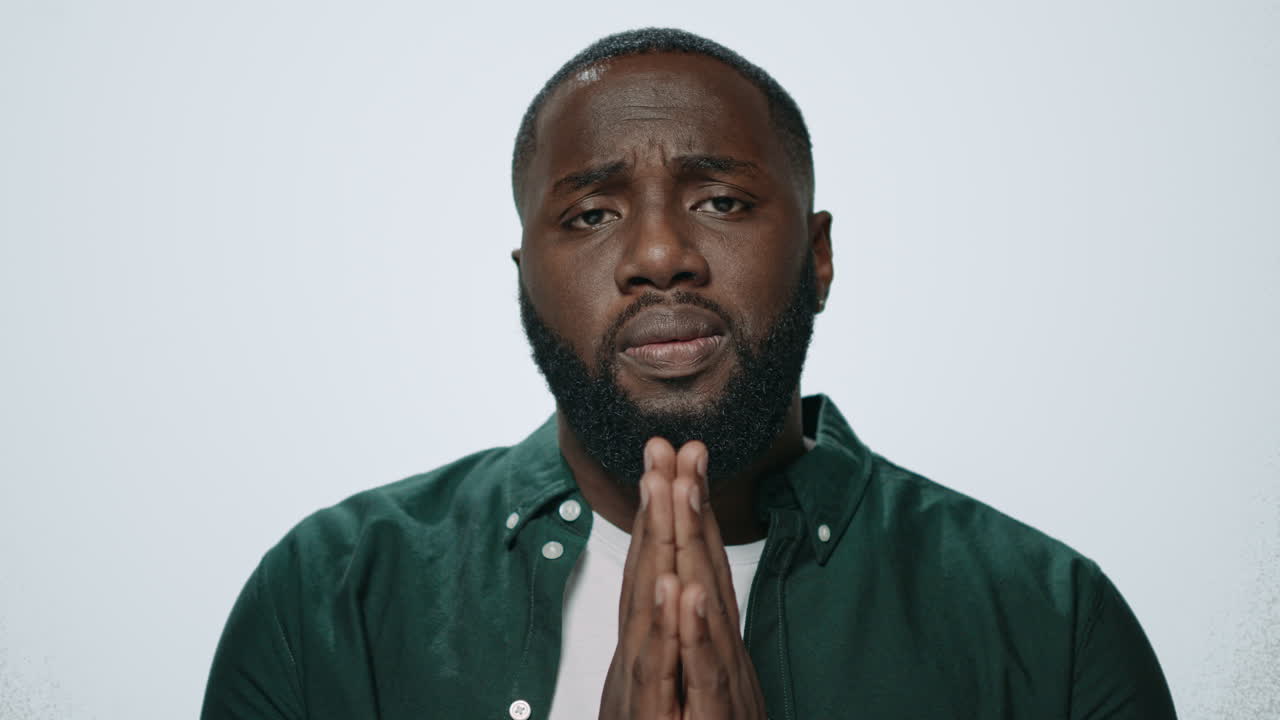 Portrait of african american man praying on grey background. Meditation concept